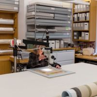 Lucy Commoner investigating a textile using a stereomicroscope in the textile conservation laboratory,  Cooper Hewitt, Smithsonian Design Museum